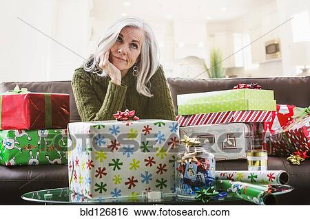 Stock Photograph - Irritated Caucasian woman wrapping Christmas gifts. Fotosearch