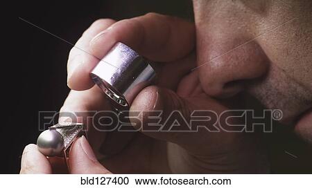 Stock Image - Jeweller exaning ring with loupe close-up. Fotosearch