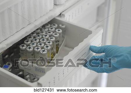 Stock Image - Lab technician opening freezer full of test tubes in laboratory close-up of hand. Fotosearch