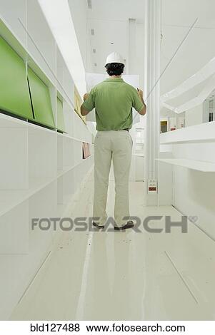 Male architect looking at plan in recently finished office building View Large Photo Image Stock Photo - Male architect looking at plan in recently finished office building. Fotosearch