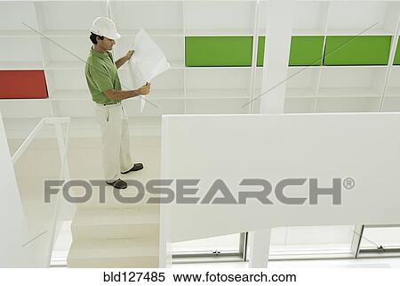 Male architect looking at plan in recently finished office building View Large Photo Image Stock Photography - Male architect looking at plan in recently finished office building. Fotosearch