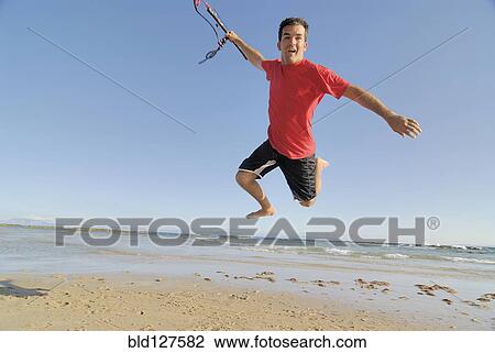 Male kite surfer jumping on beach View Large Photo Image Stock Image - Male kite surfer jumping on beach. Fotosearch