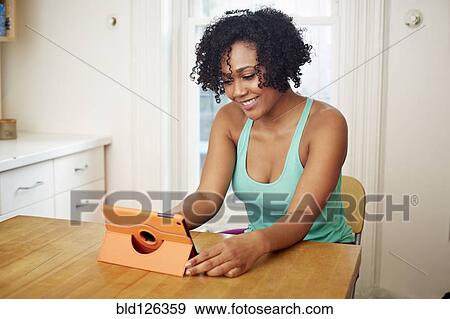 Mixed race woman using digital tablet in kitchen View Large Photo Image Stock Photo - Mixed race woman using digital tablet in kitchen. Fotosearch