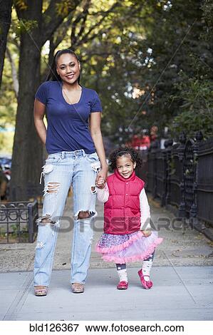 Stock Photo - Mother and daughter standing on city street. Fotosearch