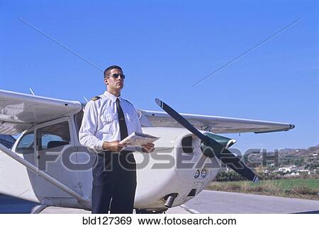 Stock Photo - Pilot Holding a Map and Standing by a Private Propeller Plane. Fotosearch