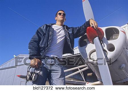 Stock Image - Pilot Standing by a Propeller Aeroplane. Fotosearch