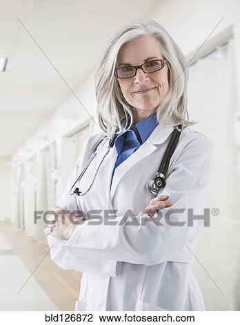 Stock Image - Portrait of confident Caucasian doctor in corridor. Fotosearch