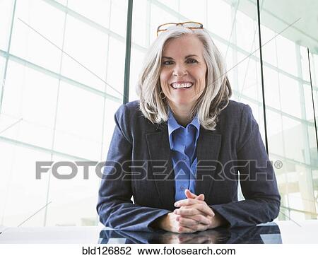 Stock Image - Portrait of confident Caucasian businesswoman at desk. Fotosearch