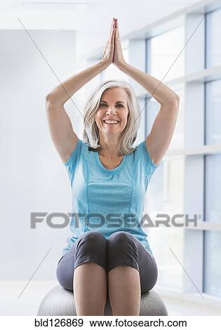 Stock Photo - Portrait of happy Caucasian woman balancing on fitness ball. Fotosearch