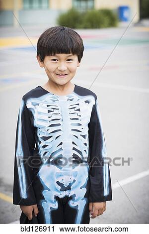 Stock Image - Portrait of Hispanic boy smiling in skeleton costume. Fotosearch