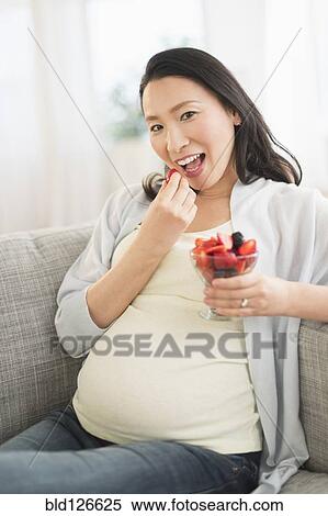 Stock Photography - Portrait of pregnant Japanese woman eating berries. Fotosearch