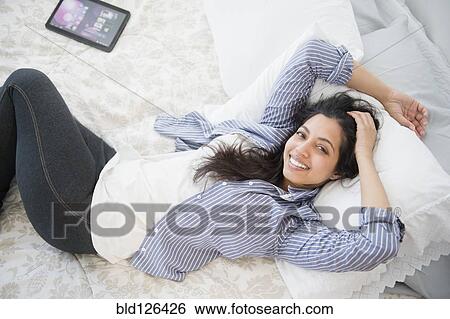 Portrait of smiling Asian woman laying on bed View Large Photo Image Stock Photograph - Portrait of smiling Asian woman laying on bed. Fotosearch