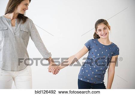 Portrait of smiling Caucasian daughter holding hands with mother View Large Photo Image Stock Image - Portrait of smiling Caucasian daughter holding hands with mother. Fotosearch