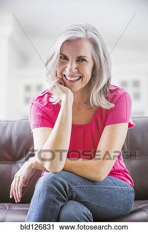 Stock Image - Portrait of smiling Caucasian woman on sofa. Fotosearch