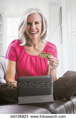 Stock Image - Portrait of smiling Caucasian woman shopping online. Fotosearch