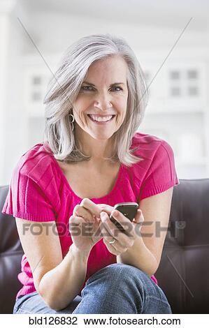 Portrait of smiling Caucasian woman text messaging on sofa View Large Photo Image Stock Image - Portrait of smiling Caucasian woman text messaging on sofa. Fotosearch