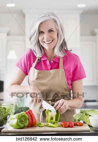 Portrait of smiling Caucasian woman slicing vegetables View Large Photo Image Stock Image - Portrait of smiling Caucasian woman slicing vegetables. Fotosearch