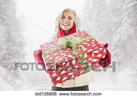 Portrait of smiling Caucasian woman with Christmas gift View Large Photo Image Stock Photo - Portrait of smiling Caucasian woman with Christmas gift. Fotosearch