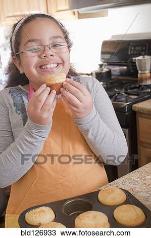 Portrait of smiling Hispanic girl eating muffin in kitchen View Large Photo Image Stock Image - Portrait of smiling Hispanic girl eating muffin in kitchen. Fotosearch