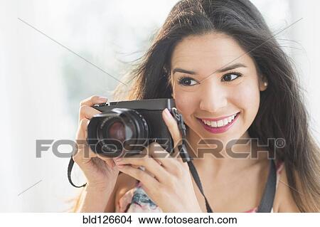 Portrait of smiling Hispanic woman holding digital camera View Large Photo Image Picture - Portrait of smiling Hispanic woman holding digital camera. Fotosearch