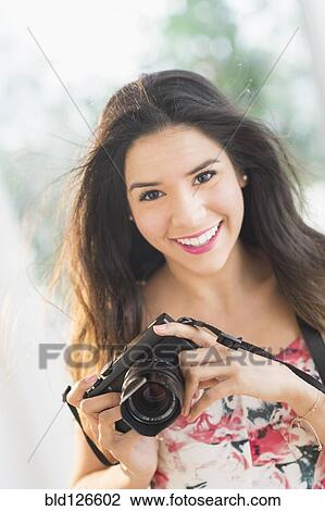 Portrait of smiling Hispanic woman holding digital camera View Large Photo Image Stock Image - Portrait of smiling Hispanic woman holding digital camera. Fotosearch