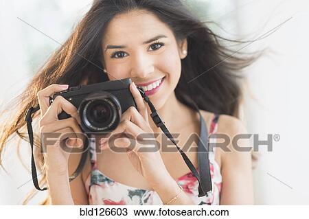 Portrait of smiling Hispanic woman holding digital camera View Large Photo Image Stock Image - Portrait of smiling Hispanic woman holding digital camera. Fotosearch