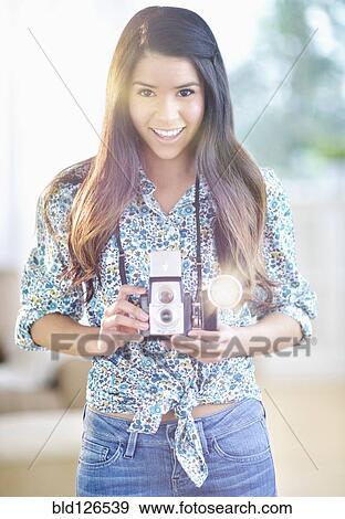 Stock Photo - Portrait of smiling Hispanic woman with antique camera. Fotosearch