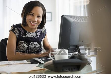 Portrait of smiling mixed race businesswoman at computer View Large Photo Image Stock Image - Portrait of smiling mixed race businesswoman at computer. Fotosearch