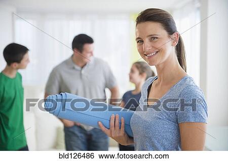 Stock Photograph - Portrait of smiling woman holding yoga mat. Fotosearch