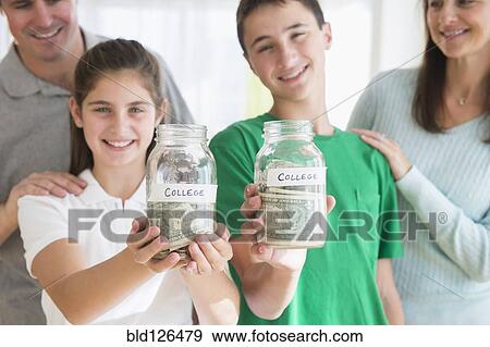 Proud Caucasian parents watching children with college savings jars View Large Photo Image Stock Photo - Proud Caucasian parents watching children with college savings jars. Fotosearch