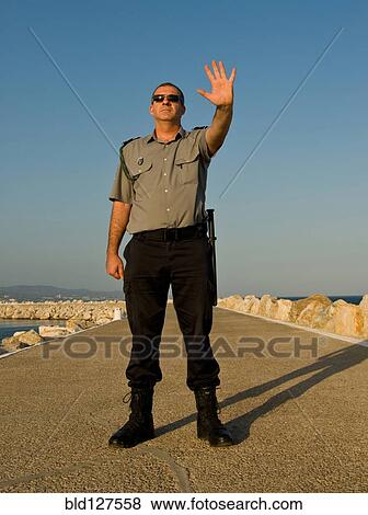 Security guard standing on concrete pier with hand raised View Large Photo Image Stock Photo - Security guard standing on concrete pier with hand raised. Fotosearch