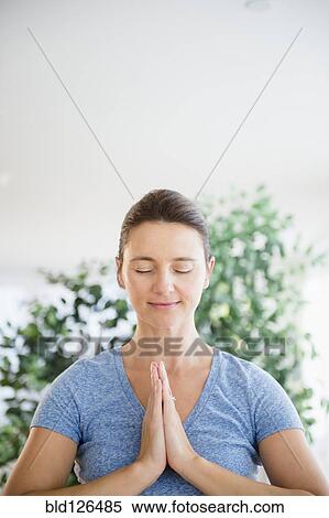 Stock Photography - Serene Caucasian woman with hands in prayer position. Fotosearch
