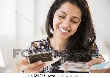 Smiling Asian woman looking at photographs View Large Photo Image Stock Photo - Smiling Asian woman looking at photographs. Fotosearch
