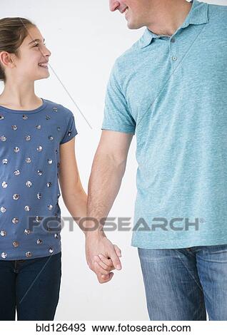 Stock Image - Smiling Caucasian father and daughter holding hands. Fotosearch