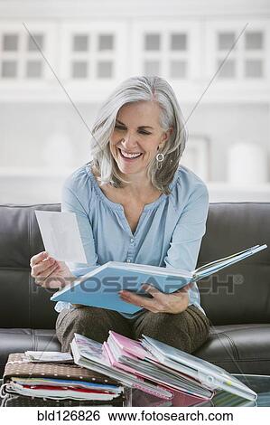 Smiling Caucasian woman looking at photograph albums View Large Photo Image Stock Photograph - Smiling Caucasian woman looking at photograph albums. Fotosearch