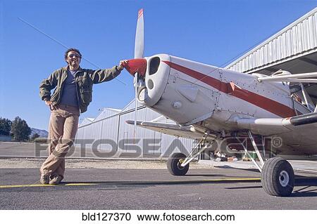 Stock Image - Smiling Man Standing Next to a Monoplane. Fotosearch