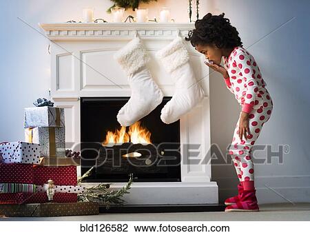 Surprised Black girl in pajamas looking down at Christmas gifts View Large Photo Image Stock Image - Surprised Black girl in pajamas looking down at Christmas gifts. Fotosearch