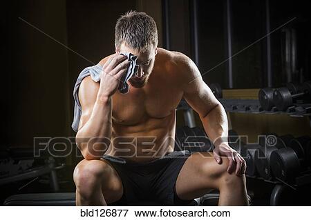 Tired Caucasian man wiping sweat off forehead in gym View Large Photo Image Stock Photo - Tired Caucasian man wiping sweat off forehead in gym. Fotosearch