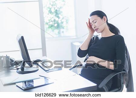 Tired pregnant Japanese businesswoman at desk View Large Photo Image Stock Photo - Tired pregnant Japanese businesswoman at desk. Fotosearch