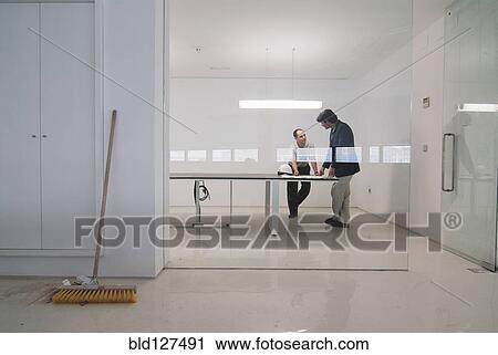 Stock Image - Two men in conference room of new office. Fotosearch