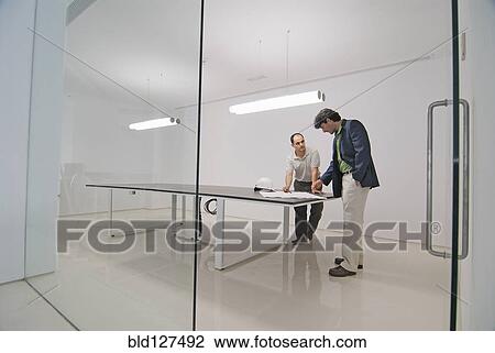 Stock Image - Two men in conference room of new office. Fotosearch