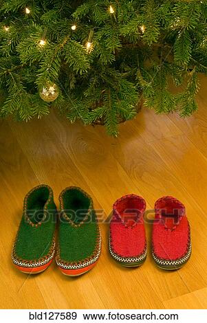 Stock Photo - Two pairs of slippers under Christmas tree. Fotosearch