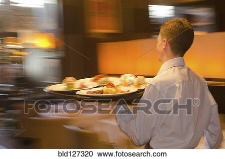 Waiter carrying tray with dishes through resturant View Large Photo Image Stock Image - Waiter carrying tray with dishes through resturant. Fotosearch
