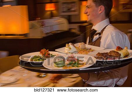 Waiter carrying tray with dishes through resturant View Large Photo Image Stock Image - Waiter carrying tray with dishes through resturant. Fotosearch