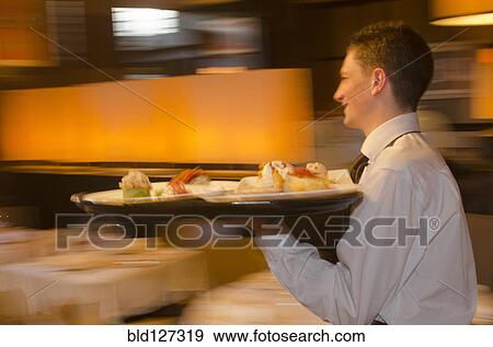 Waiter carrying tray with dishes through resturant View Large Photo Image Stock Photo - Waiter carrying tray with dishes through resturant. Fotosearch