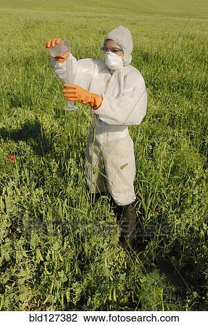 Woman in boiler suit standing in field pouring liquid into test tube View Large Photo Image Stock Image - Woman in boiler suit standing in field pouring liquid into test tube. Fotosearch