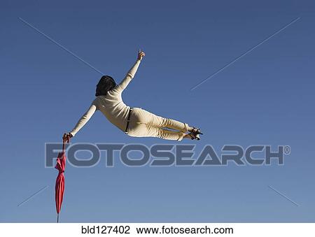 Woman in mid air clicking heels holding umbrella rear view View Large Photo Image Stock Image - Woman in mid air clicking heels holding umbrella rear view. Fotosearch