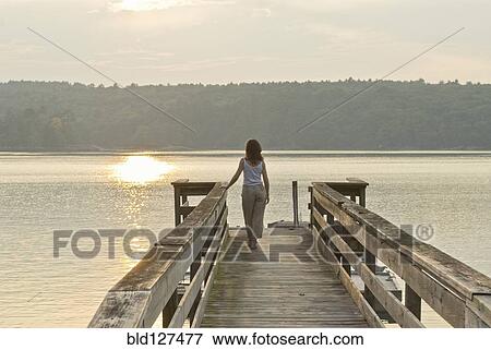 Stock Photo - woman looking out to sea from jetty. Fotosearch