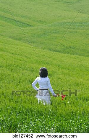 Stock Image - Woman standing in field rear view. Fotosearch