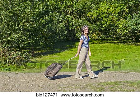 woman walking though park pulling roller case View Large Photo Image Stock Image - woman walking though park pulling roller case. Fotosearch